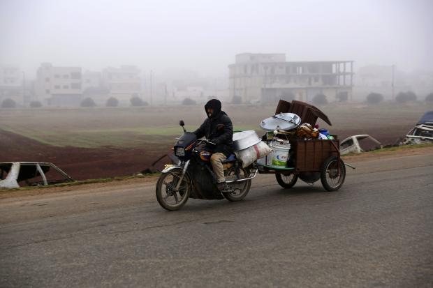 Man carrying household items on motorbike in Syria