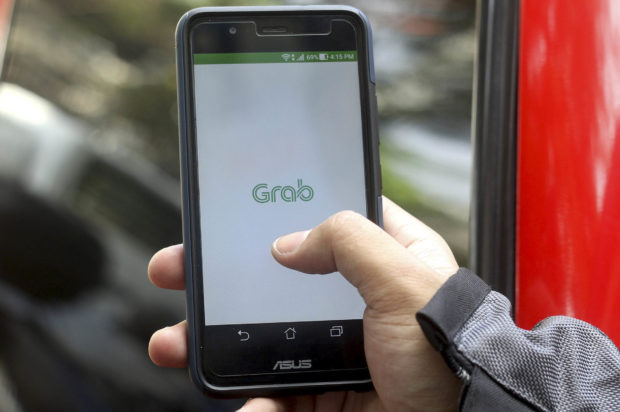 A commuter books a vehicle via the ride-hailing app Grab in Manila. This photo was taken on April 12, 2018. STORY: Grab PH slapped anew with P9-million fine