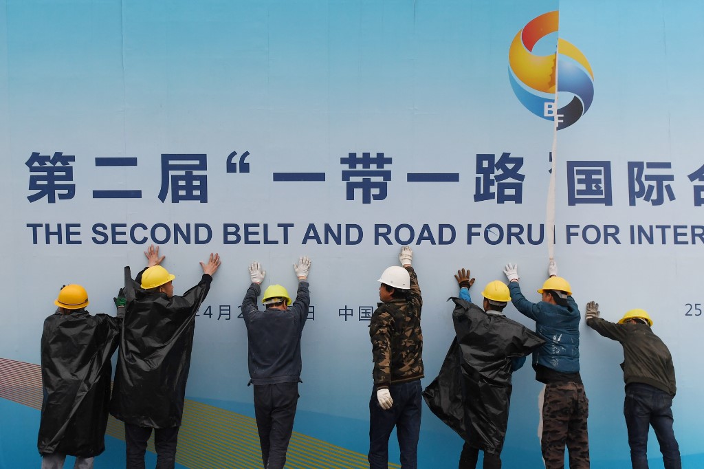 Workers take down a Belt and Road Forum panel outside the venue of the forum in Beijing on April 27, 2019. - Chinese President Xi Jinping urged dozens of world leaders on April 27 to reject protectionism and invited more countries to participate in his global infrastructure project after seeking to ease concerns surrounding the programme. (Photo by GREG BAKER / AFP)