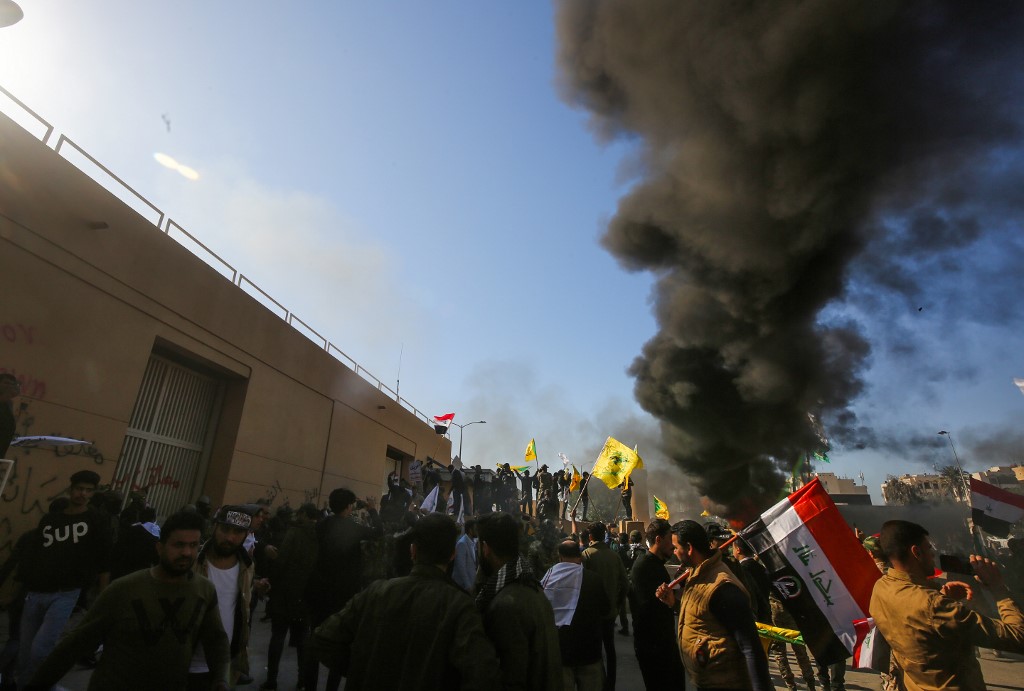 (FILES) In this file photo taken on December 31, 2019 Iraqi protesters burn tires in front of the US embassy building in the capital Baghdad to protest against the weekend's air strikes by US planes on several bases belonging to the Hezbollah brigades near Al-Qaim, an Iraqi district bordering Syria. - The United States on January 6, 2020 slammed Russia and China for their failure to condemn an attack last week on its Baghdad embassy by pro-Iranian demonstrators. (Photo by Ahmad AL-RUBAYE / AFP)