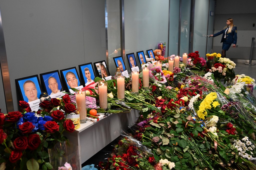 An employee walks in background of a makeshift memorial set up for the victims of the Ukraine International Airlines Boeing 737-800 that crashed near the Iranian capital Teheran, at the Boryspil airport outside Kiev, on January 11, 2020. - Ukraine demanded on January 11, 2020 that Iran punishes those guilty for the downing of a Ukrainian airliner and compensate victims while praising Tehran for cooperating with the "objective" investigation. (Photo by Sergei SUPINSKY / AFP)