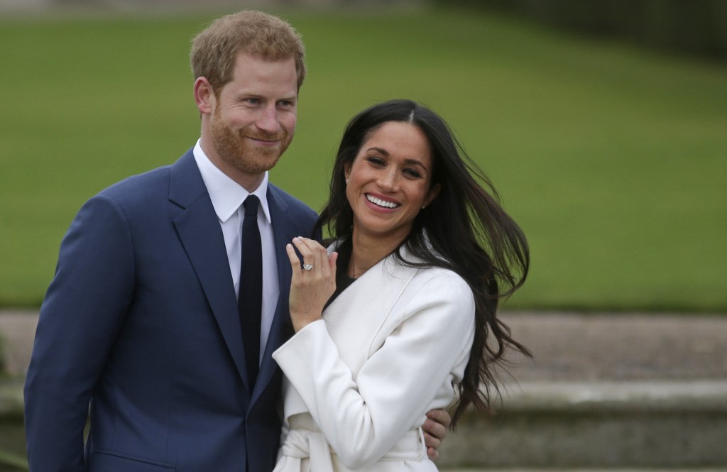 (FILES) In this file photo taken on on November 27, 2017, Britain's Prince Harry stands with his fiancee US actress Meghan Markle as she shows off her engagement ring whilst they pose for a photograph in the Sunken Garden at Kensington Palace in west London, following the announcement of their engagement. - Britain's Prince Harry and his wife Meghan will give up their titles and stop receiving public funds following their decision to give up front-line royal duties, Buckingham Palace said on January 18, 2020. "The Sussexes will not use their HRH titles as they are no longer working members of the Royal Family," the Palace said, adding that the couple have agreed to repay some past expenses. (Photo by Daniel LEAL-OLIVAS / AFP)