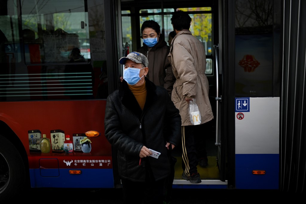 People wearing protective masks get off a bus in Beijing on January 22, 2020. - A new virus that has killed nine people, infected hundreds and already reached the United States could mutate and spread, China warned January 22, as authorities scrambled to contain the disease during the Lunar New Year travel season. (Photo by WANG Zhao / AFP)