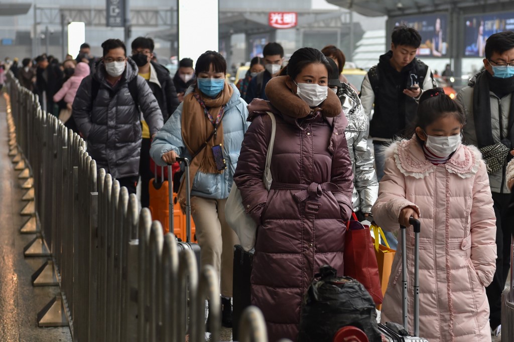 People wearing masks arrive at Hongqioa train station as they head home for the Lunar New Year in Shanghai on January 23, 2020 - China placed the city at the centre of a virus outbreak under effective quarantine, suspending outward flights and trains in a drastic step to contain a contagious disease that has killed 17, stricken hundreds and reached other countries. (Photo by HECTOR RETAMAL / AFP)