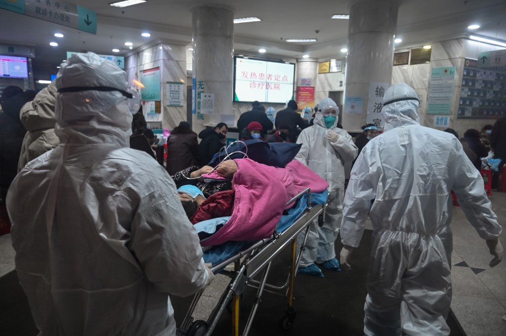 In this photo taken on January 25, 2020, medical staff wearing protective clothing to protect against a previously unknown coronavirus arrive with a patient at the Wuhan Red Cross Hospital in Wuhan. - The number of confirmed deaths from a viral outbreak in China has risen to 54, with authorities in hard-hit Hubei province on January 26 reporting 13 more fatalities and 323 new cases. (Photo by Hector RETAMAL / AFP)