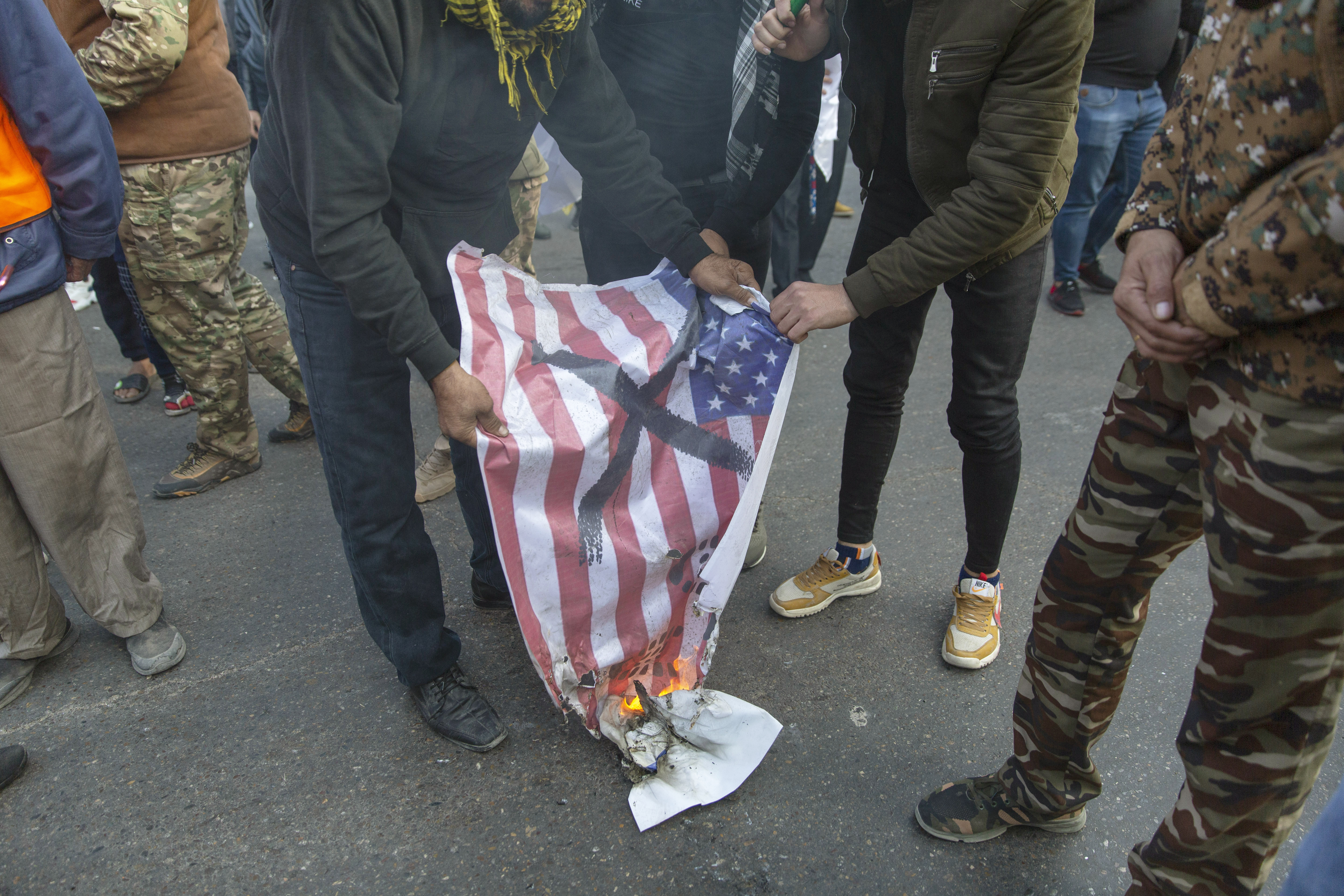 Mourners burn a U.S. flag during the funeral of Iran's top general Qassem Soleimani and Abu Mahdi al-Muhandis, deputy commander of Iran-backed militias in Iraq known as the Popular Mobilization Forces, in Baghdad, Iraq, Saturday, Jan. 4, 2020. Thousands of mourners chanting "America is the Great Satan" marched in a funeral procession Saturday through Baghdad for Iran's top general and Iraqi militant leaders, who were killed in a U.S. airstrike. (AP Photo/Nasser Nasser)