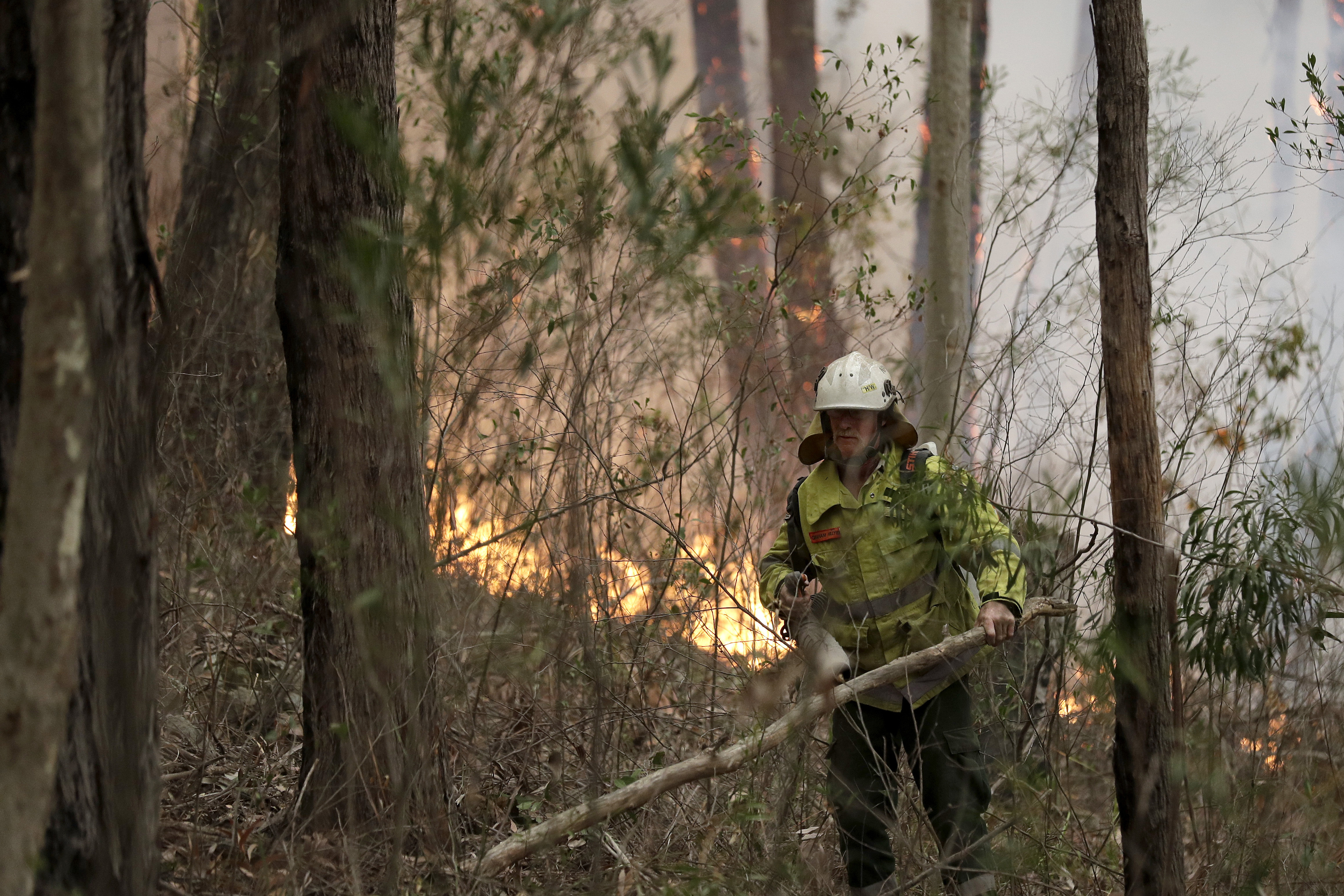 A firefighter keeps an eye on a controlled burn used to control a larger fire near Burrill Lake, Australia, Sunday, Jan. 5, 2020. Milder temperatures Sunday brought hope of a respite from wildfires that have ravaged three Australian states, destroying almost 2,000 homes. (AP Photo/Rick Rycroft)