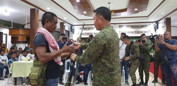 Brig. Gen. Juvy Max Uy, 6th IID assistant division commander, receives a rifle from one of the BIFF members who surrender to military authorities in Maguindanao. CONTRIBUTED PHOTO