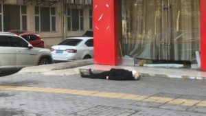 A grey-haired man wearing a face mask lies dead on the pavement at ground zero of China's virus epidemic, a plastic shopping bag in one hand. AGENCE FRANCE-PRESSE