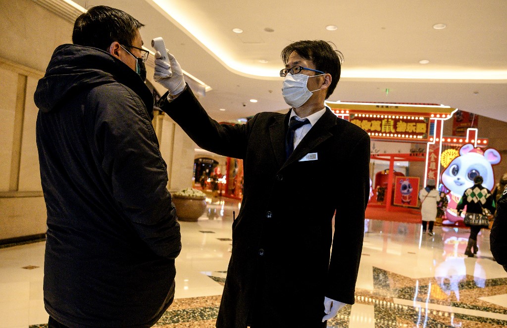 A security guard checks the temperature of a a man at a mall in Shanghai on February 8, 2020. - The new coronavirus that emerged in a Chinese market at the end of last year has killed more than 700 people and spread around the world. (Photo by NOEL CELIS / AFP)
