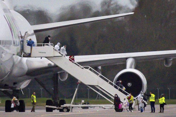 People with masks disembark from plane in UK