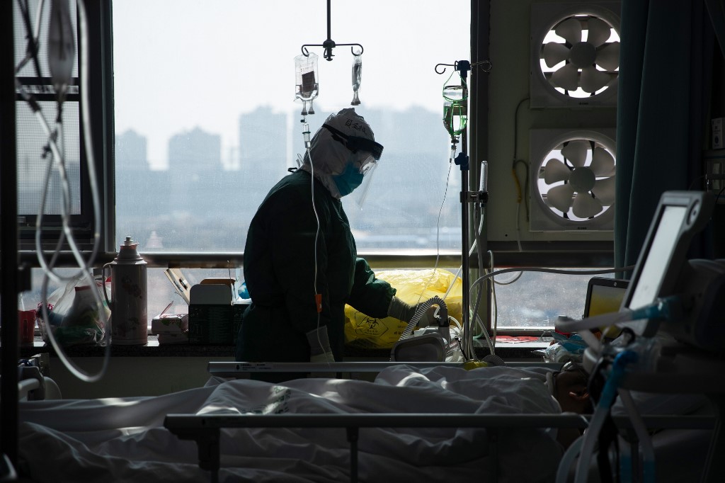 This photo taken on February 22, 2020 shows a medical staff member treating a patient infected by the COVID-19 coronavirus at a hospital in Wuhan in China's central Hubei province. - Authorities in Wuhan on February 24 reversed a decision that would have allowed some people to leave the quarantined city at the centre of China's deadly virus epidemic. (Photo by STR / AFP) / China OUT