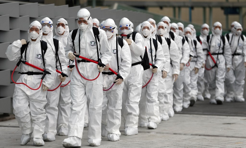 South Korean soldiers wearing protective gear move to spray disinfectant as part of preventive measures against the spread of the COVID-19 coronavirus, at Dongdaegu railway station in Daegu on February 29, 2020. - South Korea confirmed 594 more coronavirus cases on February 29, the biggest increase to date for the country and taking the national total to 2,931 infections with three additional deaths. (Photo by - / YONHAP / AFP) / - South Korea OUT / REPUBLIC OF KOREA OUT  NO ARCHIVES  RESTRICTED TO SUBSCRIPTION USE