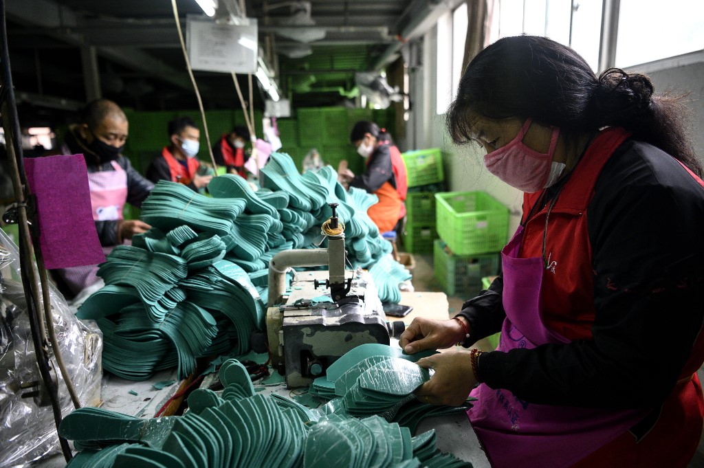 (FILES) This file photo taken on February 27, 2020 shows workers wearing protective facemasks as a preventive measure against the COVID-19 coranavirus, making insoles at the Zhejiang Xuda Shoes Co. factory in Wenzhou. - China's coronavirus epidemic turned a Lunar New Year family reunion into an endless quarantine for factory worker Hu Aihua, preventing him from returning to work in another province. (Photo by NOEL CELIS / AFP) / TO GO WITH HEALTH-VIRUS-CHINA-ECONOMY-EMPLOYMENT BY BEIYI SEOW