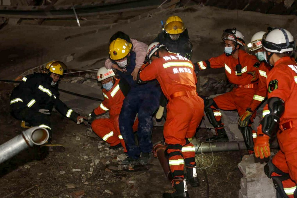 A woman (on the back) is rescued from the rubble of a collapsed hotel in Quanzhou, in China's eastern Fujian province on March 7, 2020. - Around 70 people were trapped after the Xinjia Hotel collapsed on March 7 evening, officials said. (Photo by STR / AFP) / China OUT