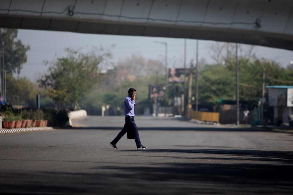 A man walks across a deserted road during the first day of a 21-day government-imposed nationwide lockdown as a preventive measure against the COVID-19 coronavirus in New Delhi on March 25, 2020. - India's billion-plus population went into a three-week lockdown on March 25, with a third of the world now under orders to stay indoors, as the coronavirus pandemic forced Japan to postpone the Olympics until next year. (Photo by Xavier GALIANA / AFP)