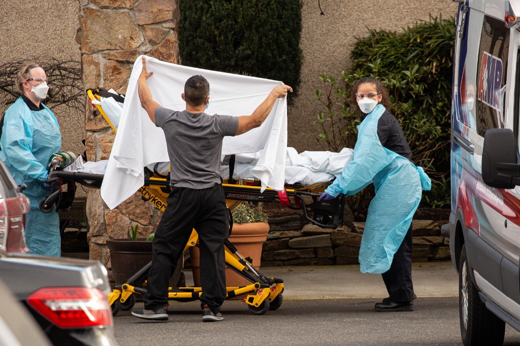 SEATTLE, WA - FEBRUARY 29: Healthcare workers transport a patient on a stretcher into an ambulance at Life Care Center of Kirkland in Kirkland, Washington. Dozens of staff and residents at Life Care Center of Kirkland are reportedly exhibiting coronavirus-like symptoms, with two confirmed cases of (COVID-19) associated with the nursing facility reported so far.   David Ryder/Getty Images/AFP