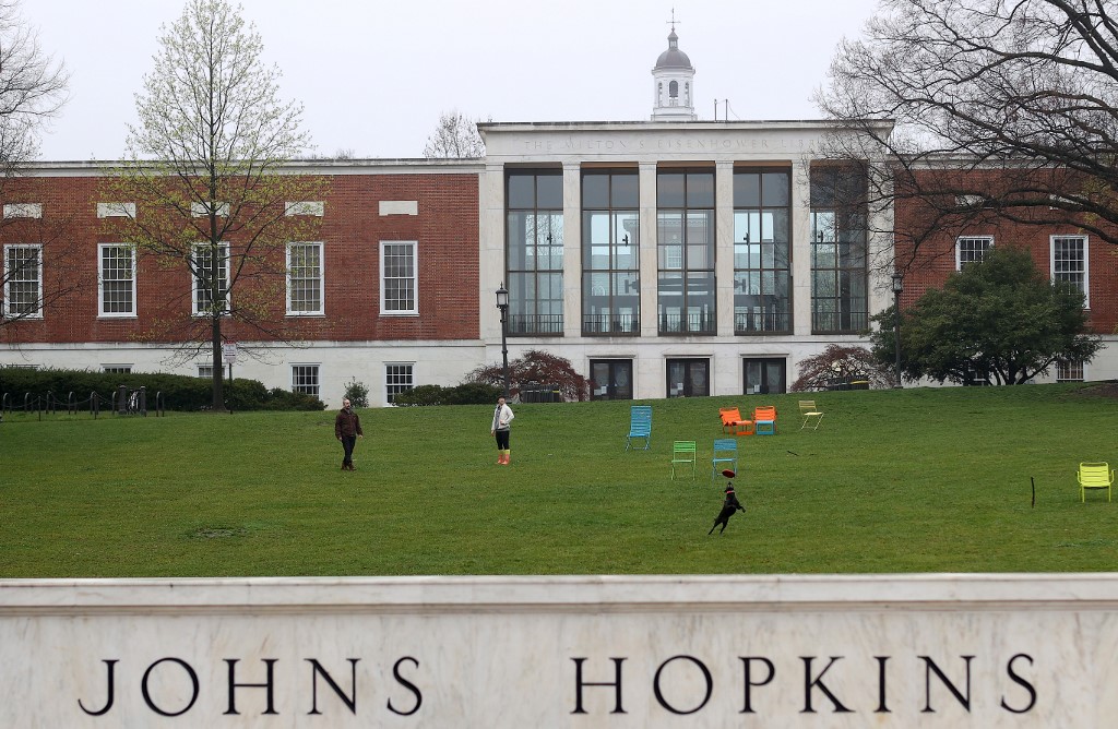 BALTIMORE, MARYLAND - MARCH 28: A couple throw a frisbee for a dog on the campus of The Johns Hopkins University on March 28, 2020 in Baltimore, Maryland. The school is shut down due to the coronavirus (COVID-19) outbreak.   Rob Carr/Getty Images/AFP