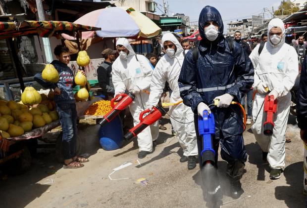  Workers using disinfectant in market in Gaza City