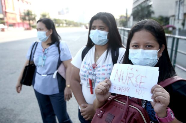 Stranded health workers show note ‘Im a nurse, pasabay po!’ at the intersection of EDSA and Roxas boulevard in Pasay City to go to Cardinal Santos Medical Center in Greenhills