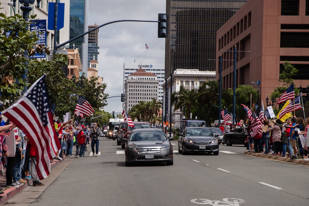 Cars, some waving US flags, drive through a rally in downtown San Diego against California's stay at home order to prevent the spread of the novel coronavirus, which causes COVID-19, on April 18, 2020. - Hundreds protested Saturday in cities across America against coronavirus-related lockdowns -- with encouragement from President Donald Trump -- as resentment grows against the crippling economic cost of confinement. (Photo by ARIANA DREHSLER / AFP)