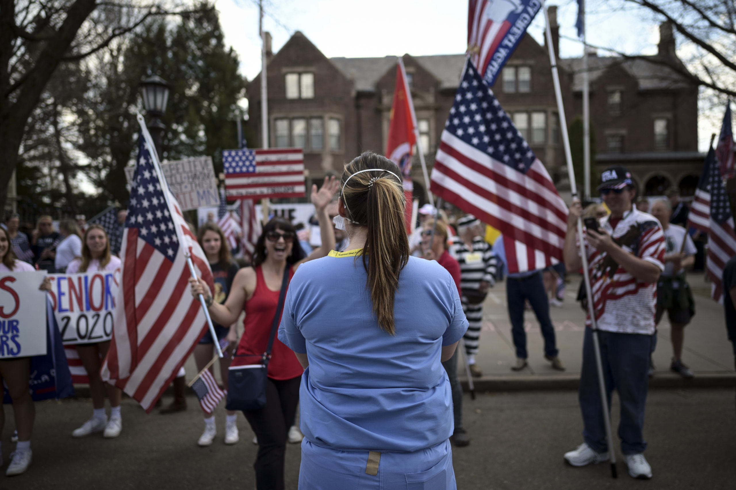 A woman who identified herself as a registered nurse in a local emergency room counterprotests in front of a demonstration to open up the state from the restrictions in place due to the new coronavirus, organized by the 3% United Patriots group, outside the Governor's Mansion, Saturday, April 25, 2020, in St. Paul, Minn. (Aaron Lavinsky/Star Tribune via AP)