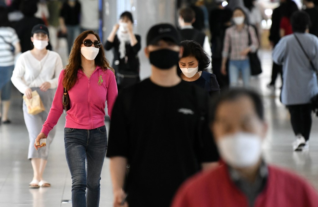 People wearing face masks walk through an underground shopping area in Seoul on May 6, 2020. - South Korea returned largely to normal on May 6 as workers went back to offices, and museums and libraries reopened under eased social distancing rules after new coronavirus cases dropped to a trickle. (Photo by Jung Yeon-je / AFP)
