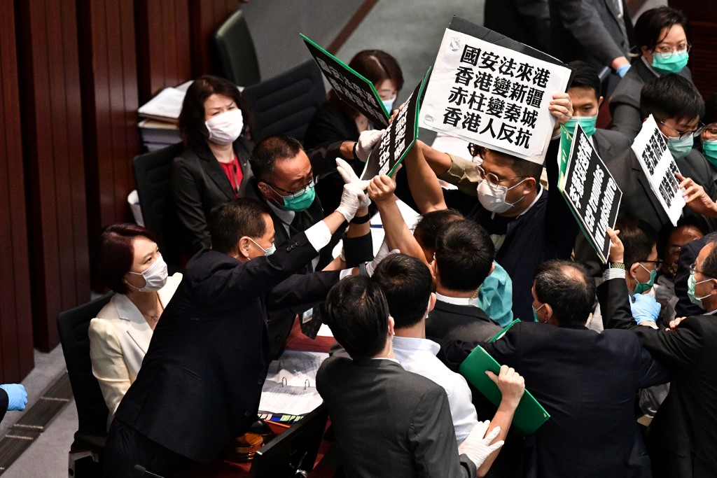 Hong Kong pro-democracy lawmakers holding up placards are blocked by security as they protest during a House Committee meeting, chaired by pro-Beijing lawmaker Starry Lee (L-in white jacket), concerning the second reading of a national anthem bill, at the Legislative Council in Hong Kong on May 22, 2020. - A proposal to enact new Hong Kong security legislation was submitted to China's rubber-stamp on May 22, state media said, a move expected to fan fresh protests in the semi-autonomous financial hub. (Photo by Anthony WALLACE / AFP)