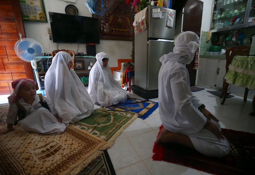 A Muslim family offer prayers inside their home as they celebrate Eid al-Fitr, which marks the end of the holy month of Ramadan, in Manila on May 24, 2020. - The government has banned mass gatherings including at mosques and churches during the government's efforts to contain the spread of the COVID-19 coronavirus. (Photo by - / AFP)