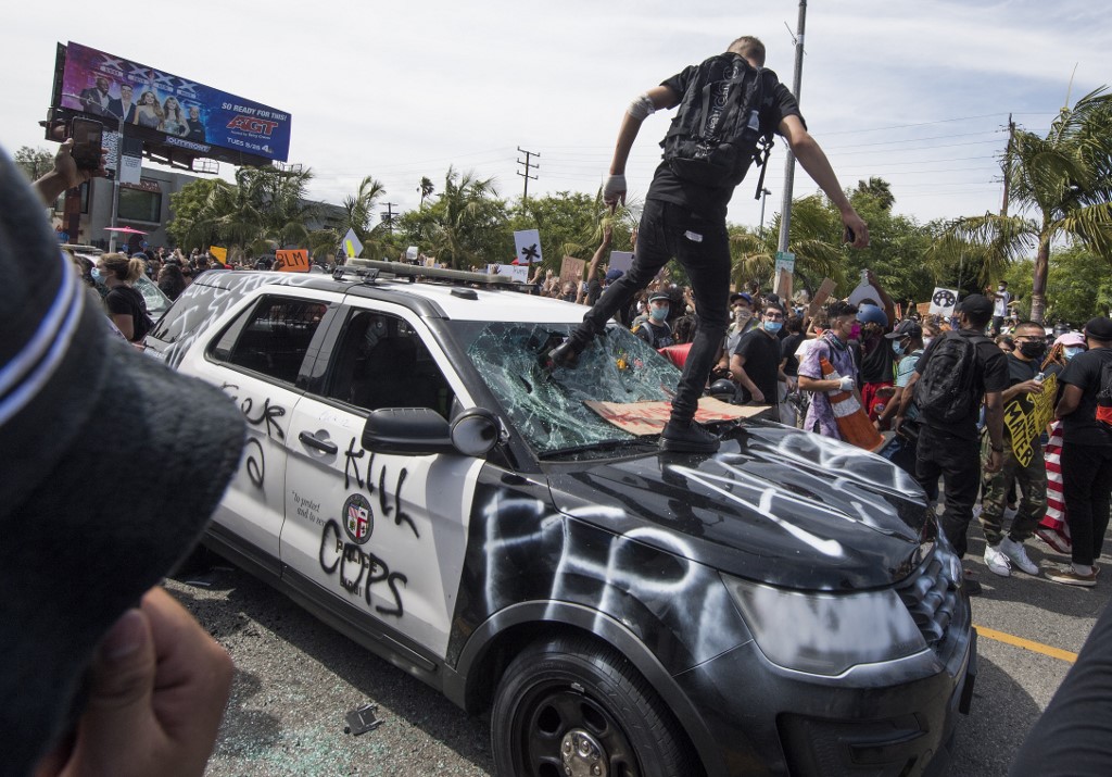 Demonstrators smash a police vehicle in the Fairfax District as they protest the death of George Floyd,  in Los Angeles, California on May 30, 2020. - Demonstrations are being held across the US after George Floyd died in police custody on May 25. (Photo by Mark RALSTON / AFP)