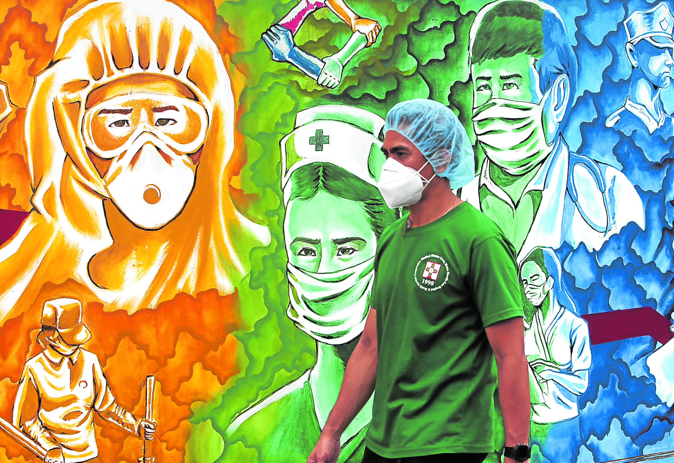 A hospital worker walks past a colorful mural honoring frontliners painted in front of the Mission hospital in Pasig City during the weekend. More than a thousand health workers have been infected with the Corona virus, 19 of them doctors since the start of the pandemic. INQUIRER/ MARIANNE BERMUDEZ