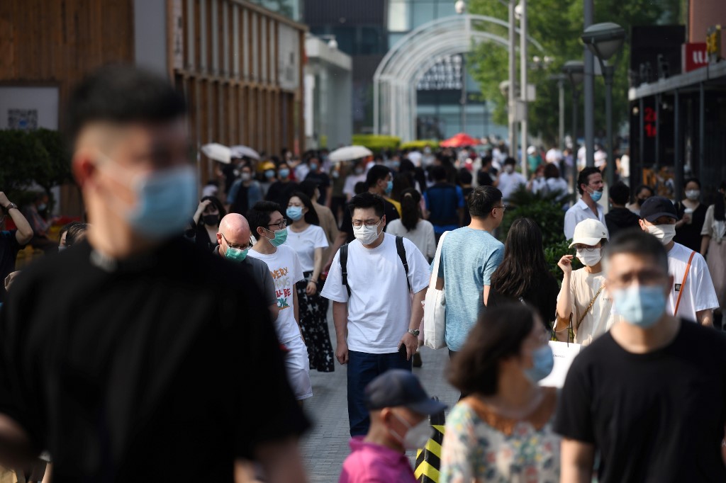 People wear face masks as a preventive measure against the COVID-19 coronavirus as they walk between shopping mall buildings in Beijing on May 2, 2020, the second day of a five-day national holiday. (Photo by GREG BAKER / AFP)