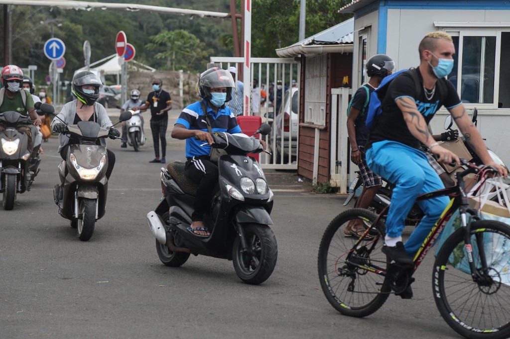 Bike and scooter passengers wearing protective face masks, make their way to board the ferry in Mamoudzou, on the French Indian Ocean island of Mayotte to sail to Petite Terre,  on June 4, 2020, as measures to curb the spread of the COVID-19 (novel coronavirus) are maintained on Mayotte over concerns about the continued spread of the virus there and a fragile health system. (Photo by Ali AL-DAHER / AFP)