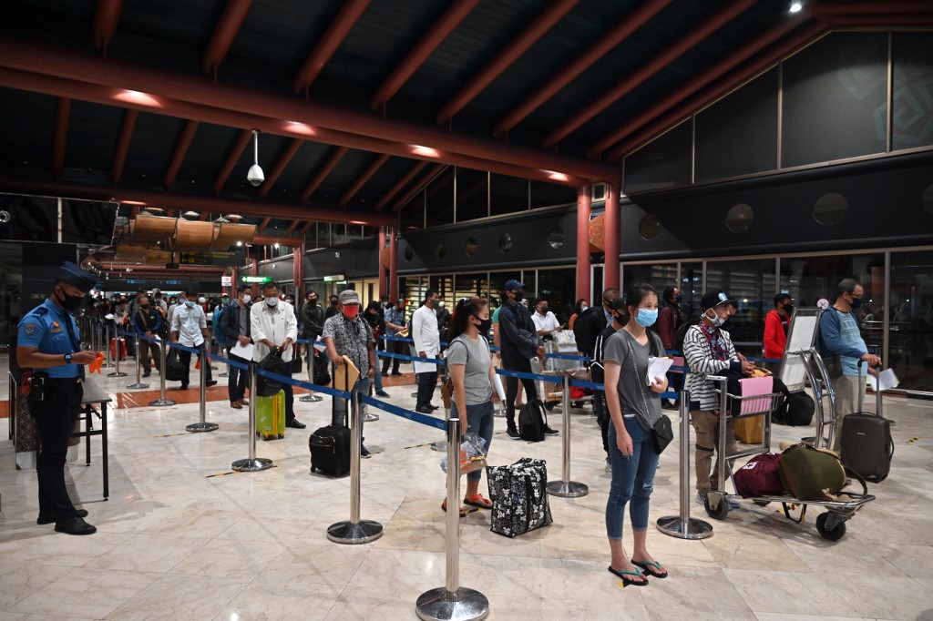 This picture taken on June 4, 2020 shows travellers queueing to have their documents checked prior to taking a flight at Sukarno-Hatta airport in Tangerang near Jakarta. - Cabin crew in protective suits, health certification for passengers, mandatory face masks, and longer check-in times. Welcome to the new reality of mass air travel. (Photo by ADEK BERRY / AFP) / TO GO WITH Health-virus-aviation,FOCUS by Martin Abbugao and Haeril Halim