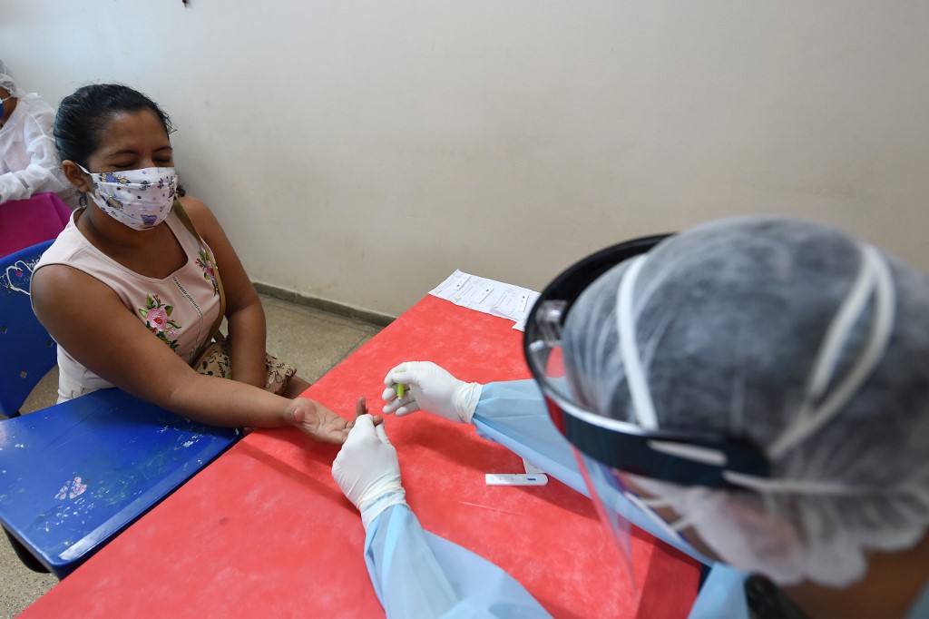 An indigenous woman of the Marubo ethnic group is tested for the novel coronavirus by a member of the medical team of the Brazilian Armed Forces at a health post in Atalaia do Norte, Amazonas state, northern Brazil, on the border with Peru, on June 20, 2020, amid the COVID-19 pandemic. - The Brazilian Armed Forces are carrying out missions aimed to halt Covid-19 spread in remote indigenous communities. (Photo by EVARISTO SA / AFP)