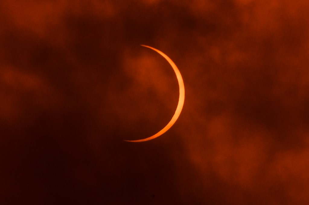 The moon moves in front of the sun during an annular solar eclipse as seen through clouds from New Delhi on June 21, 2020. (Photo by Jewel Samad / AFP)