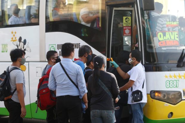 A bus conductor (R) takes the temperature of passengers about to board a bus in Manila on June 23, 2020. - The Philippine government has eased restrictions on the passenger jeepneys to help people commute to work after easing quarantine rules in the capital. (Photo by AC Dimatatac / AFP)