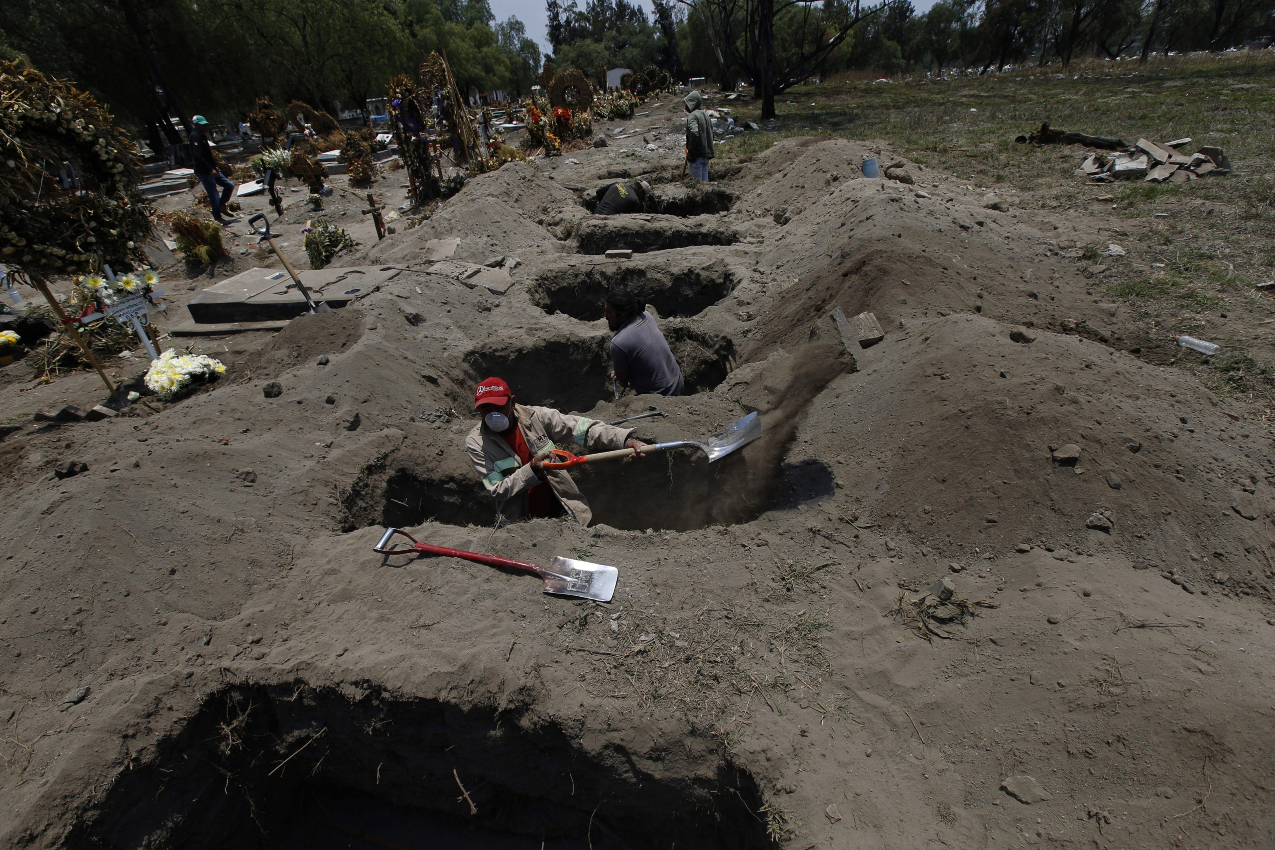 Melvin Sanaurio, front, digs a grave at the San Lorenzo Tezonco Iztapalapa cemetery in Mexico City, Tuesday, June 2, 2020, amid the new coronavirus pandemic. "It takes me more than an hour to dig one grave," Sanaurio said. (AP Photo/Marco Ugarte)