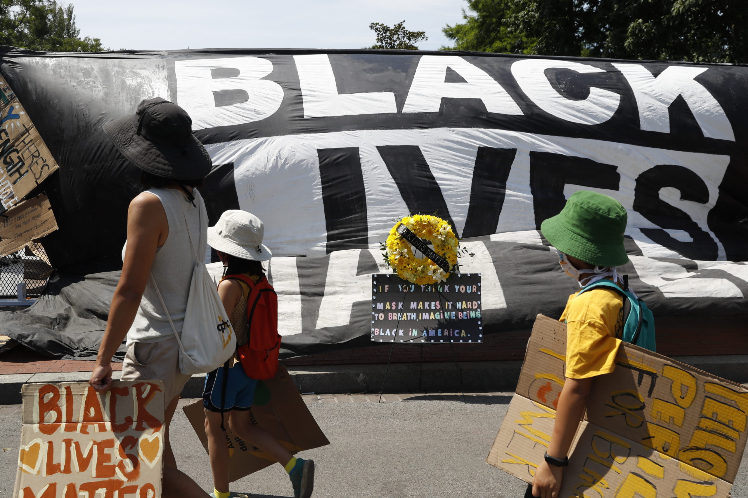 Demonstrators walk Tuesday, June 9, 2020, near the White House in Washington, past a large banner that reads Black Lives Matter, hanging on a fence at 16th and H Street, after days of protests over the death of George Floyd, a black man who was in police custody in Minneapolis. Floyd died after being restrained by Minneapolis police officers. (AP Photo/Jacquelyn Martin)