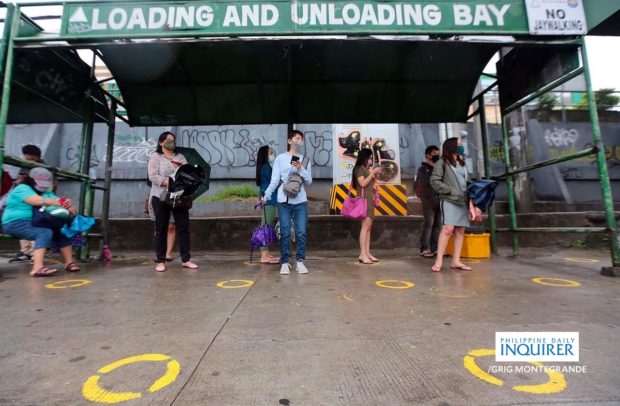 Commuters brave the rain with umbrellas while waiting for scarce transportation along Commonwealth Avenue in Quezon City