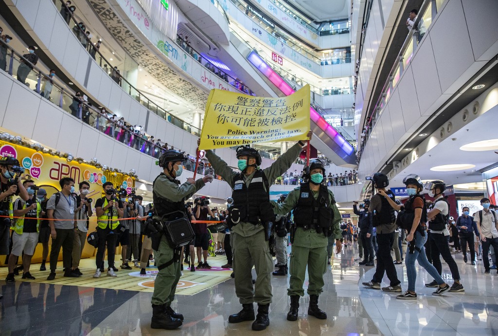 Riot police hold up a warning flag during a demonstration in a mall in Hong Kong on July 6, 2020, in response to a new national security law introduced in the city which makes political views, slogans and signs advocating Hong Kong’s independence or liberation illegal. - Hong Kongers are finding creative ways to voice dissent after Beijing blanketed the city in a new security law and police began making arrests for people displaying now forbidden political slogans. (Photo by ISAAC LAWRENCE / AFP)