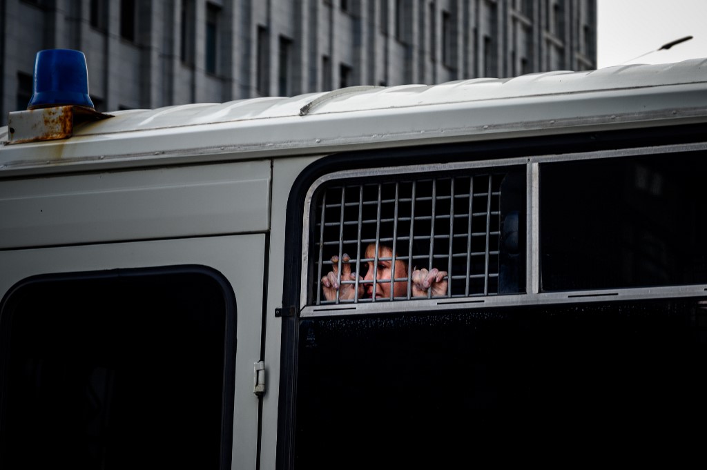A detained supporter of Ivan Safronov, a former journalist and aide to the head of Russia's space agency Roscosmos, looks out from inside a police bus in central Moscow on July 7, 2020. - A high-profile Russian journalist who became an advisor to the head of the space agency was detained on July 7, 2020 on charges of treason for divulging state military secrets, authorities said. (Photo by Dimitar DILKOFF / AFP)