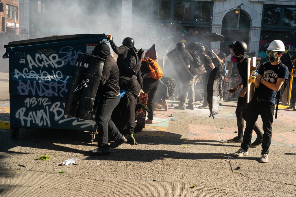 SEATTLE, WA - JULY 25: Demonstrators use dumpsters and shields for protection from police during protests in Seattle on July 25, 2020 in Seattle, Washington. Police and demonstrators clash as protests continue in the city following reports that federal agents may have been sent to the city.   David Ryder/Getty Images/AFP