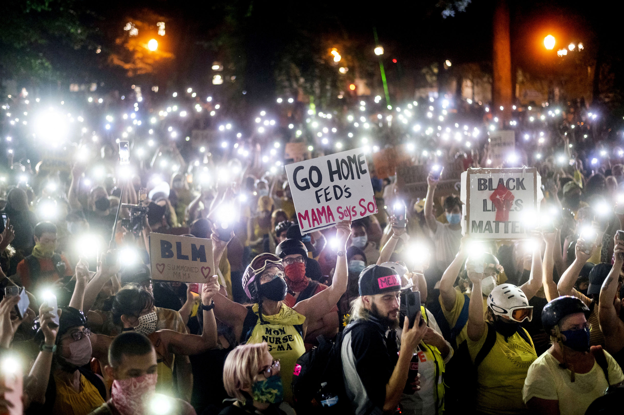 Hundreds of Black Lives Matter protesters hold their phones aloft on Monday, July 20, 2020, in Portland, Ore.  Federal officers’ actions at protests in Oregon’s largest city, hailed by President Donald Trump but done without local consent, are raising the prospect of a constitutional crisis — one that could escalate as weeks of demonstrations find renewed focus in clashes with camouflaged, unidentified agents outside Portland’s U.S. courthouse. (AP Photo/Noah Berger)