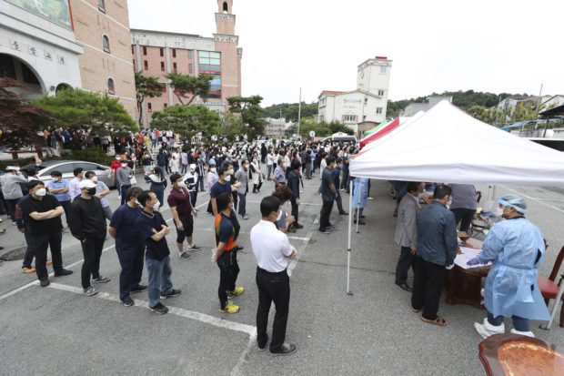 People wait in line for the new coronavirus tests at a church in Gwangju, South Korea, Friday, July 3, 2020. South Korea has reported 63 newly confirmed cases of COVID-19 as health authorities scramble to mobilize public health tools to the southwestern city of Gwangju, where more than 50 people were found sickened over the past week. Chung Hoi-sung/Yonhap via AP