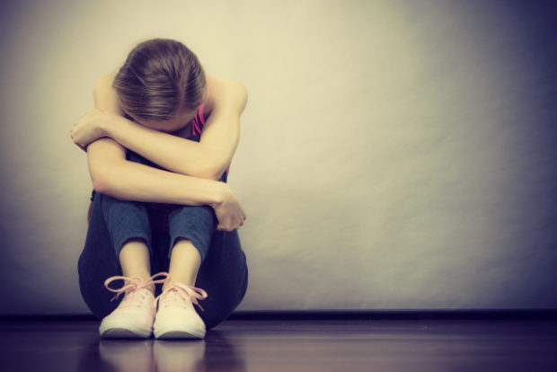 Sad depressed young teenage girl sitting by wall. STORY: Youth suicide attempts rising – UP survey