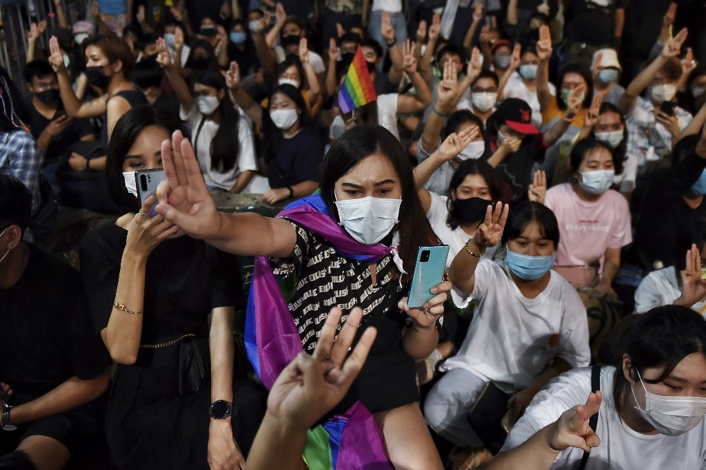 Thai LGBTQIA+ protesters and allies flash the three-fingered Hunger Games salute during an anti-government rally in front of Democracy Monument in Bangkok on July 25, 2020. (Photo by Lillian SUWANRUMPHA / AFP)