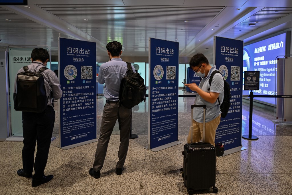 This photo taken on August 3, 2020 shows passengers checking their health codes on their phones upon arrival at Tianhe Airport in Wuhan in China’s central Hubei province. - The city's convalescence since a 76-day quarantine was lifted in April has brought life and gridlocked traffic back onto its streets, even as residents struggle to find their feet again. Long lines of customers now stretch outside breakfast stands, a far cry from the terrified crowds who queued at city hospitals in the first weeks after a city-wide lockdown was imposed in late January to curb the spread of the COVID-19 coronavirus. (Photo by Hector RETAMAL / AFP)