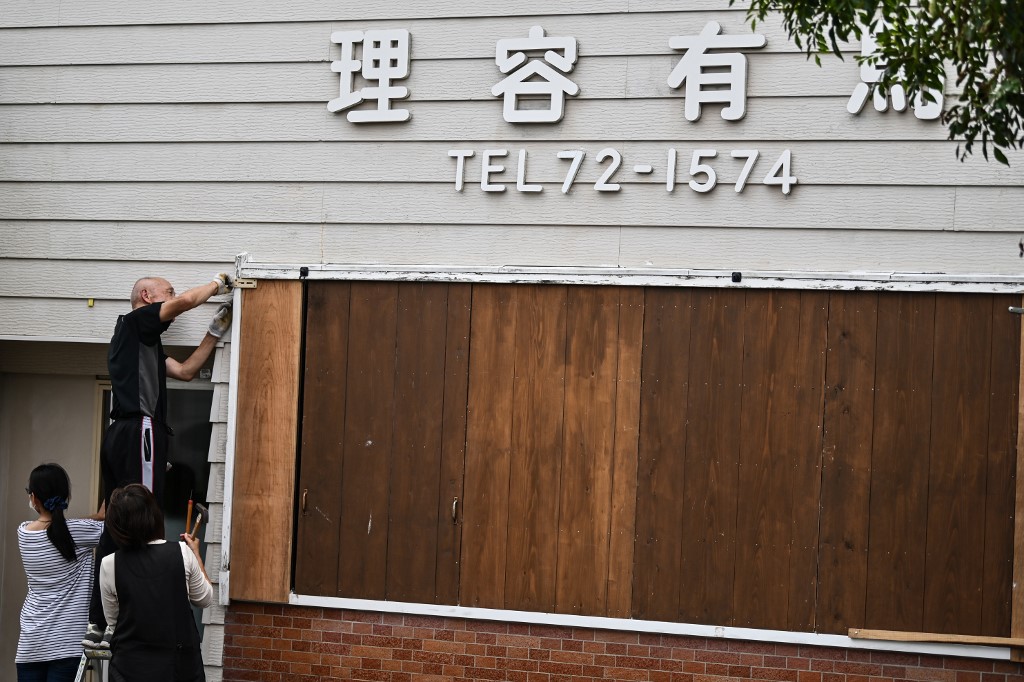 A man barricades his hair salon before Typhoon Haishen approaches in Makurazaki, Kagoshima prefecture on September 5, 2020. - Typhoon Haishen is expected to affect Japan from late September 5, with winds of up to 290 kilometres per hour (180 miles per hour), making it a "violent" storm -- the top level on the country's classification scale. (Photo by CHARLY TRIBALLEAU / AFP)