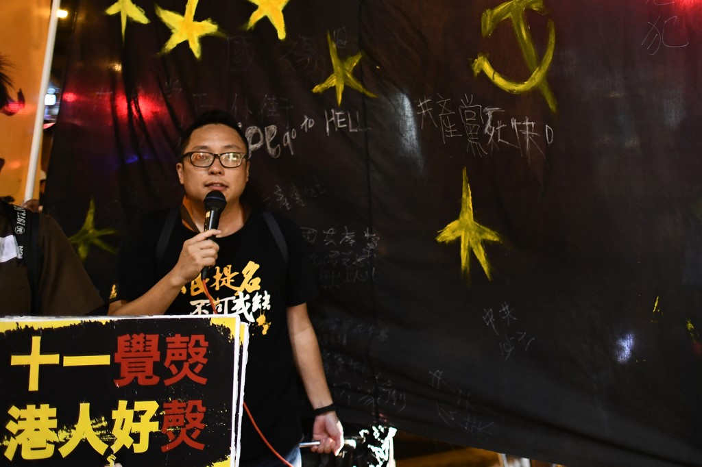 (FILES) In this file photo taken on October 1, 2017, activist Tam Tak-chi walks with a black banner towards the Chinese Liaison office after an annual protest march on China's national day, in Hong Kong. - An opposition activist was arrested by Hong Kong's new national security police unit on September 6, 2020 for "uttering seditious words", the latest detention of a high profile democracy supporter in the financial hub. (Photo by Anthony WALLACE / AFP)